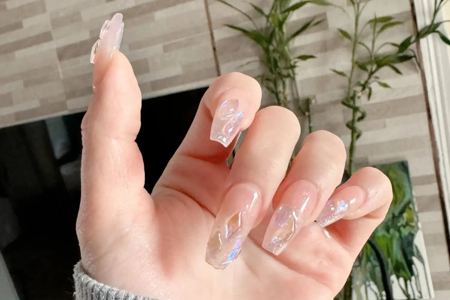 Main avec des ongles manucurés présentant un vernis à ongles transparent et brillant.